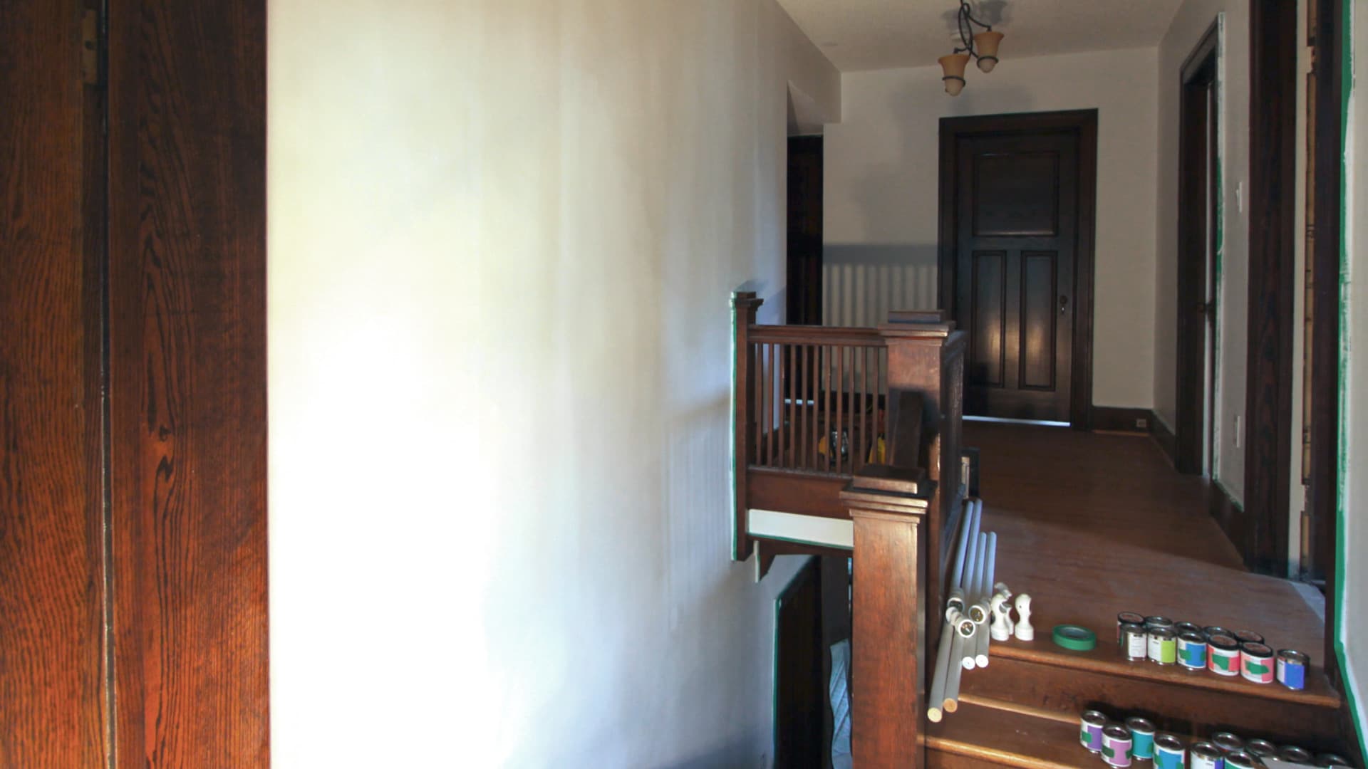 Chromatic Ascent — the prepared staircase wall, with the project's paint cans queued along the steps below.