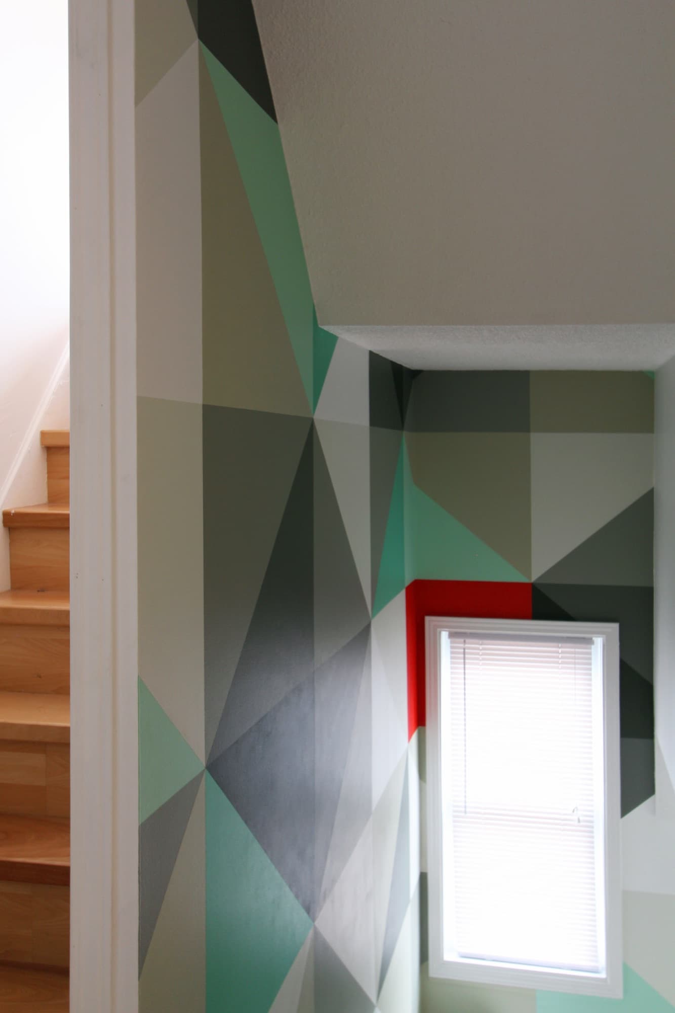 Mint & Vermillion — corner detail where the triangulated pattern turns onto the second wall and meets the ceiling.